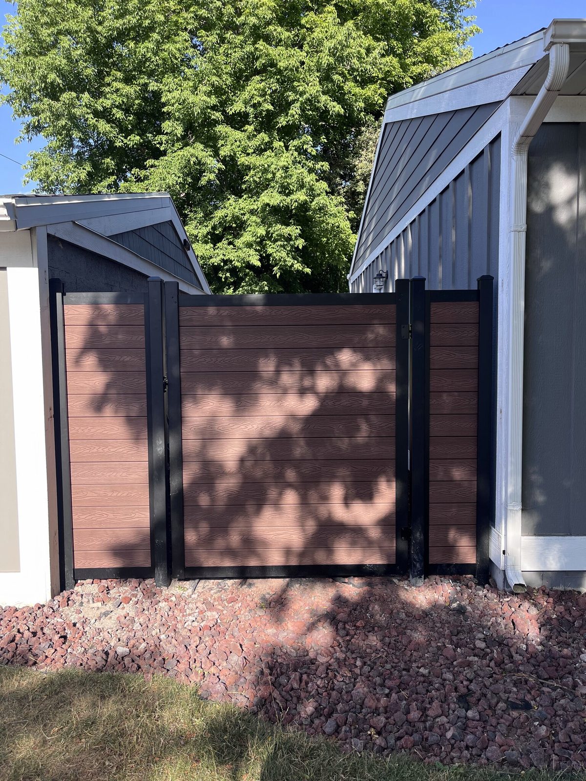 Brown composite walk gate in a black aluminum frame between two short fence panels on a Trusted Fence job in South Jordan, UT