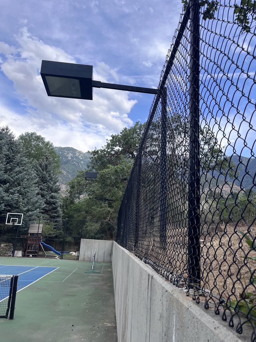 Tall black chain link fence along a sport court with a light fixture in the Salt Lake Valley