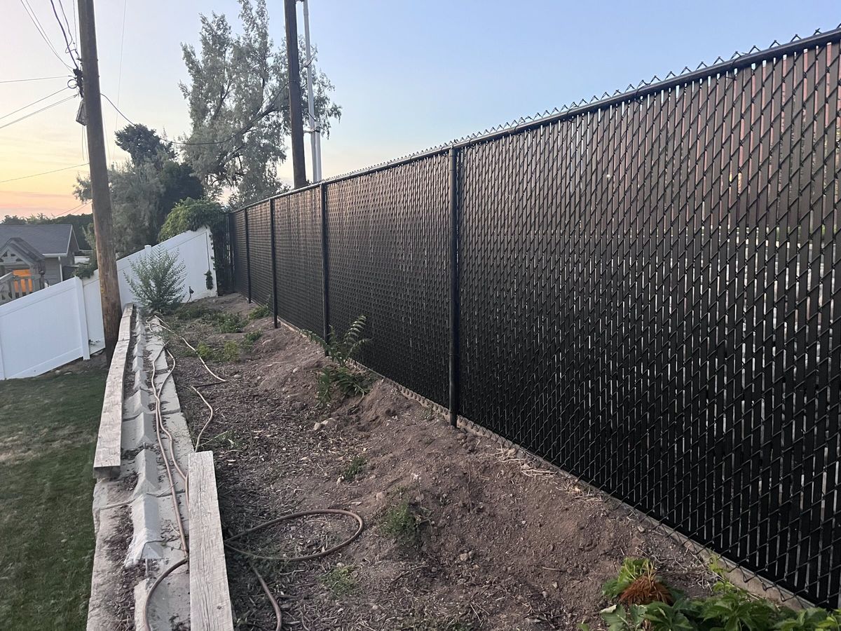 Black chain link fence with privacy slats above a raised bed at dusk in the Salt Lake Valley