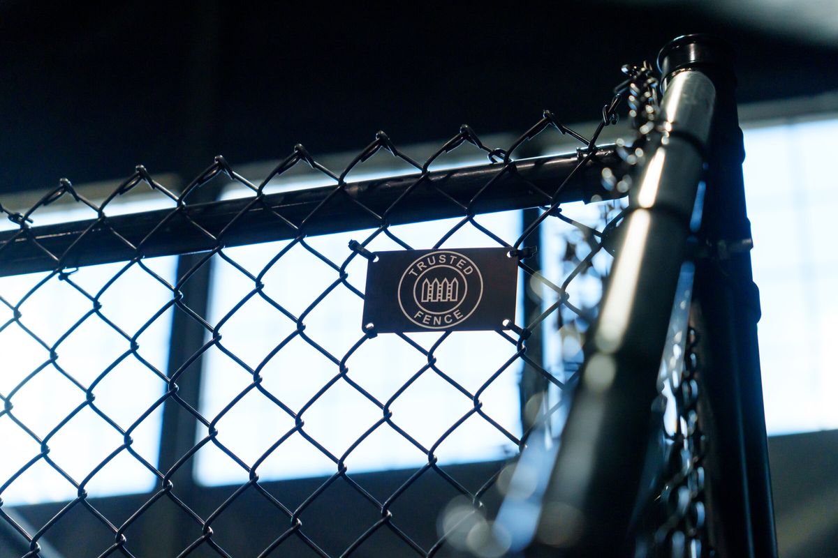Close view of a black chain link cage post and mesh inside an indoor sports facility in Salt Lake City, UT