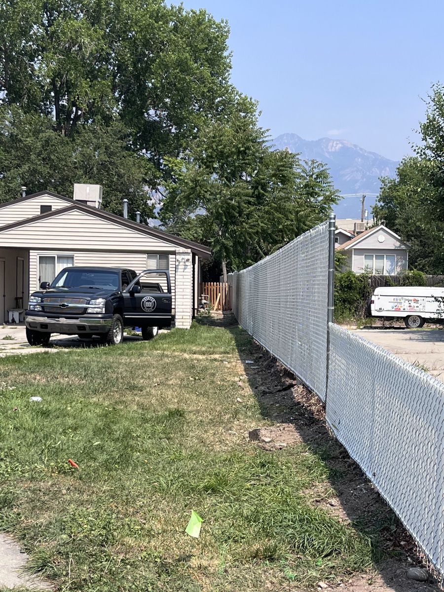 Chain link fence with light gray privacy slats beside a home with the Wasatch mountains behind in Herriman, UT