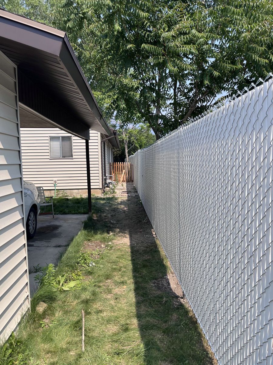 Chain link fence with light gray privacy slats along a narrow side yard in Herriman, UT