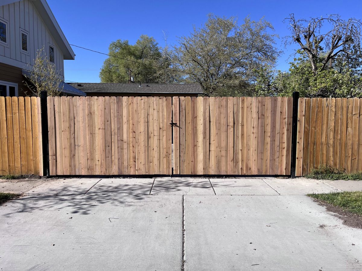 Horizontal wood fence and double drive gate across a concrete driveway in Midvale, UT