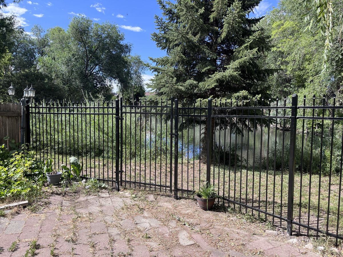 Black ornamental iron fence and double gate at a brick paver patio in Sandy, UT