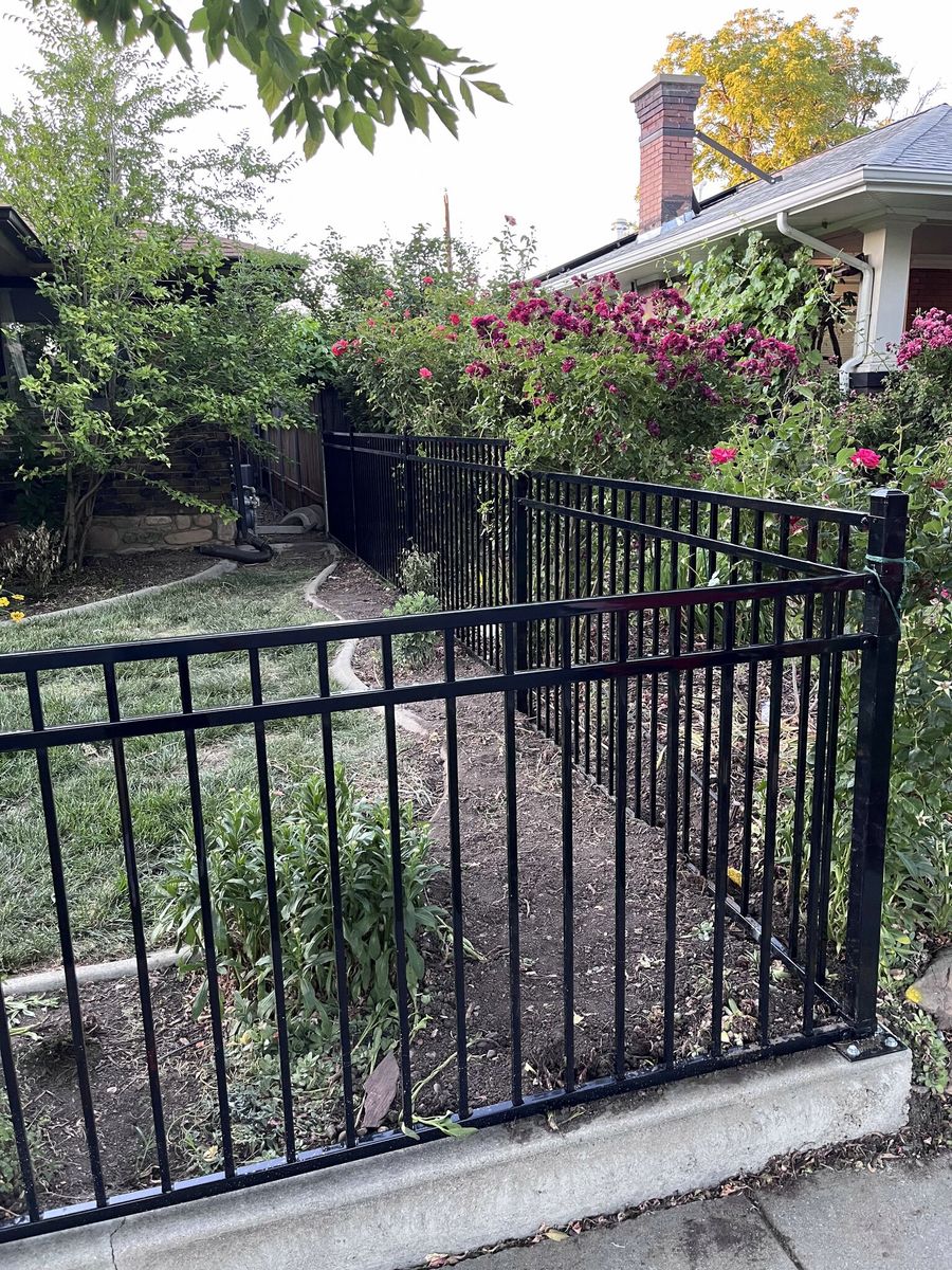 Black ornamental iron fence beside a flower garden at a home in Cottonwood Heights, UT