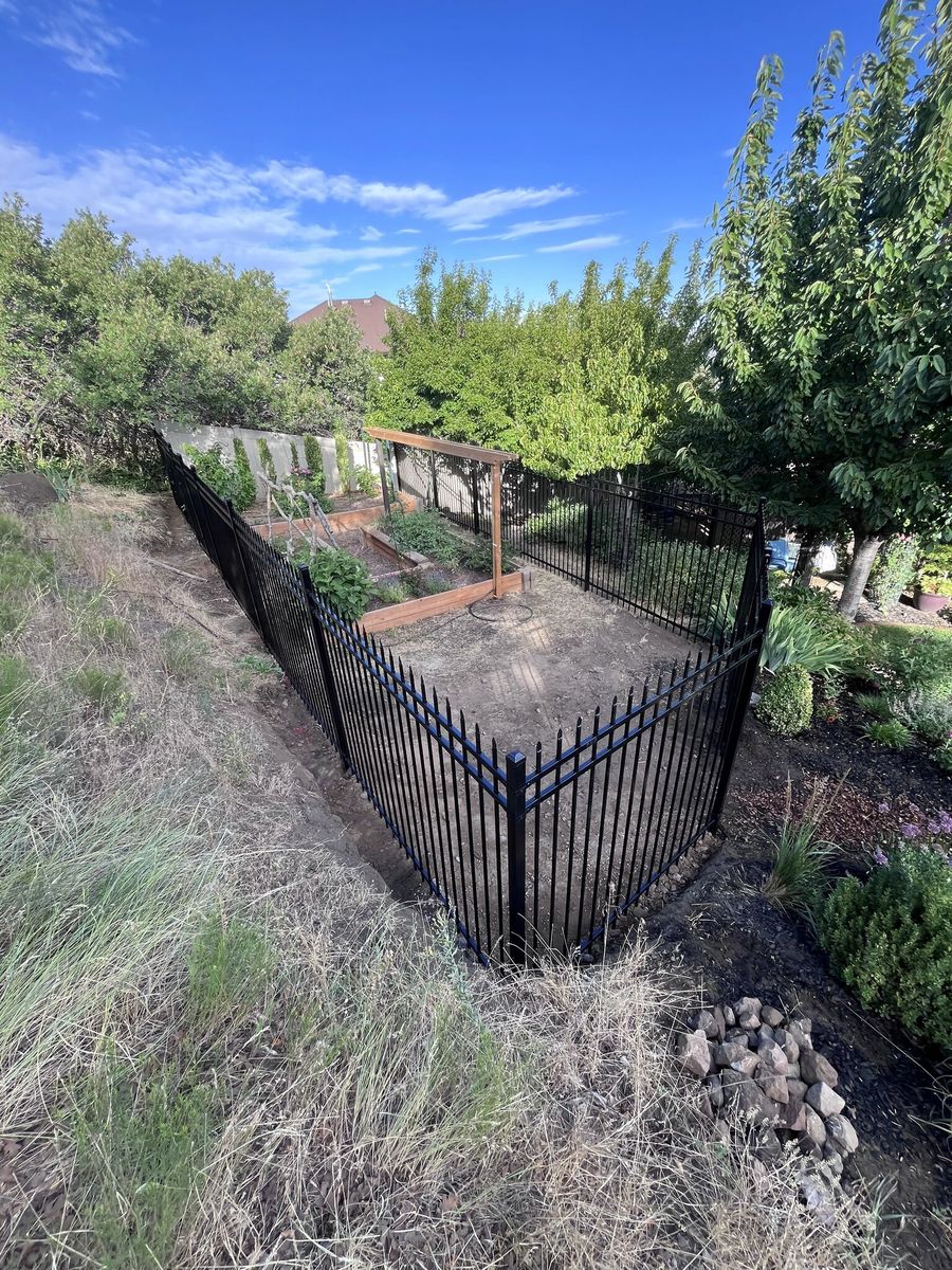 Black ornamental iron fence enclosing a backyard vegetable garden in Sandy, UT