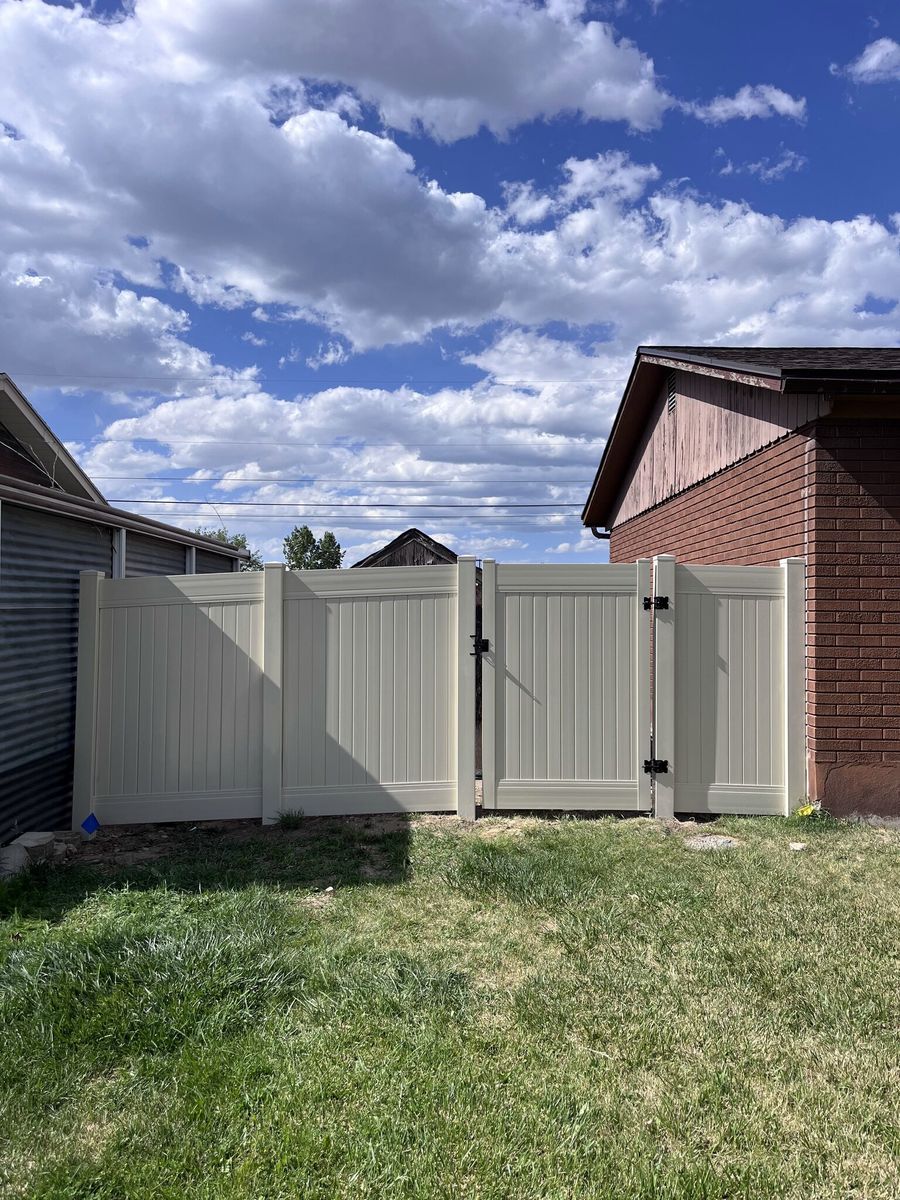 Tan vinyl privacy fence and walk gate beside a brick garage in Holladay, UT