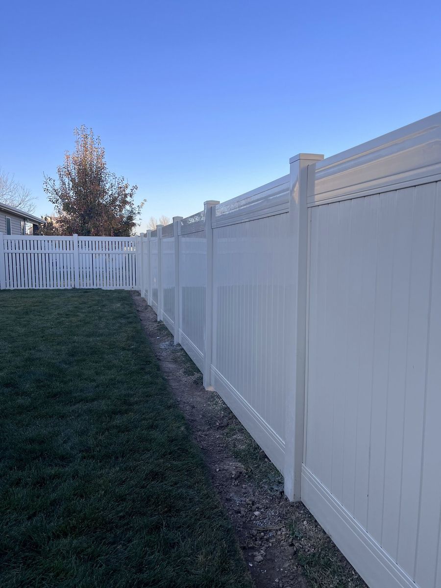 Vinyl privacy fence with a capped top running along a lawn in the Salt Lake Valley