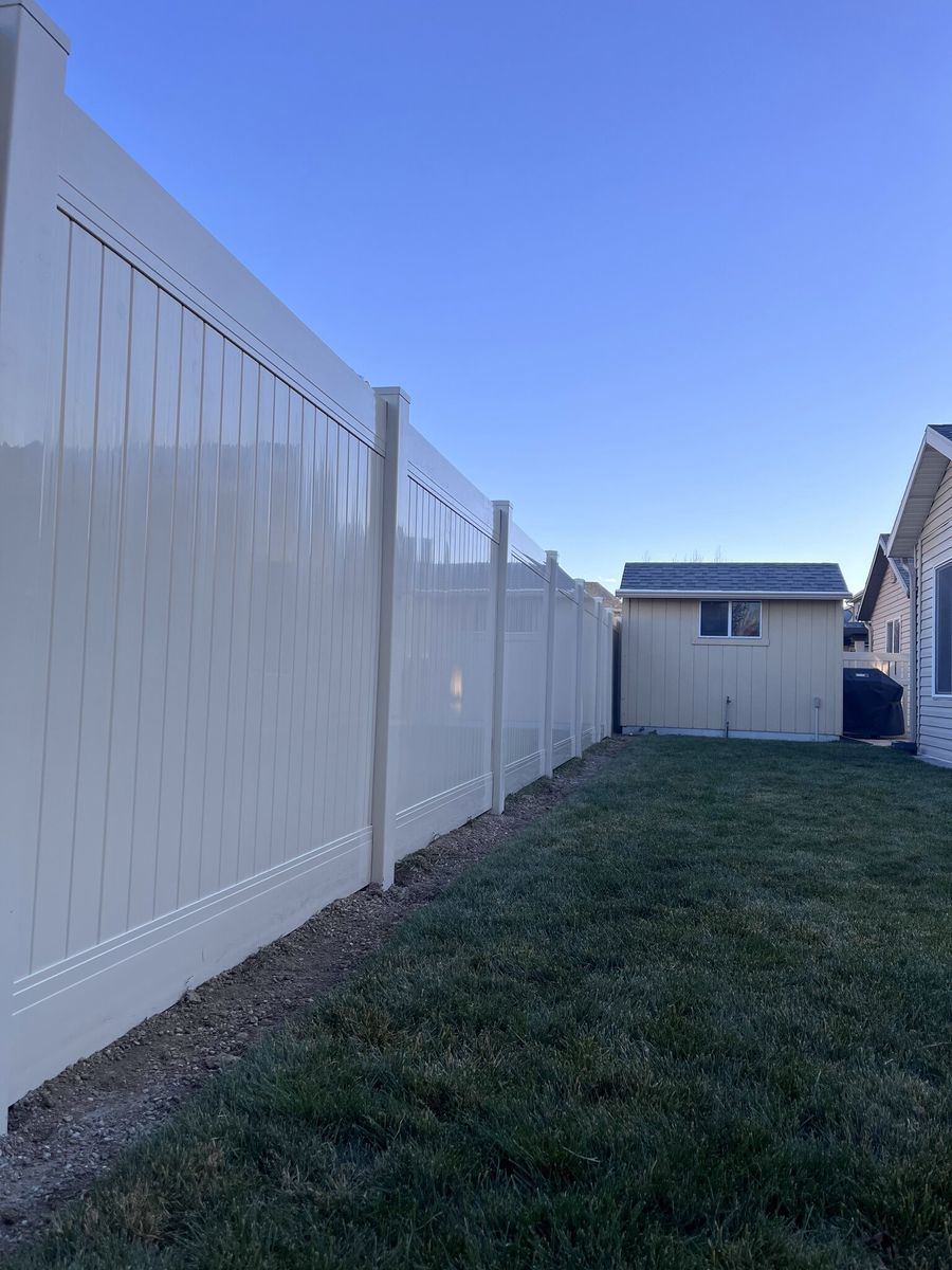 Tall vinyl privacy fence along a backyard with a shed at the end in the Salt Lake Valley