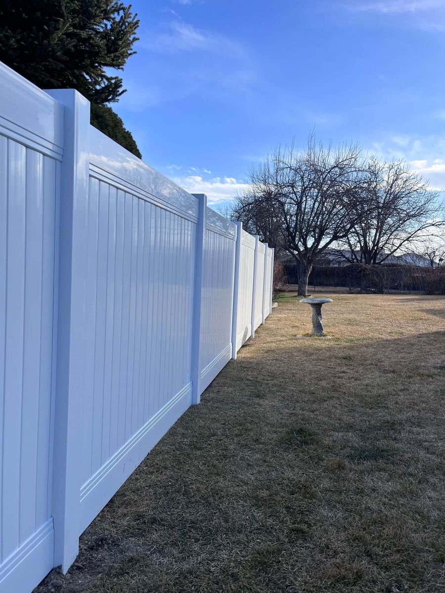 White vinyl privacy fence along a backyard property line in West Valley City, UT