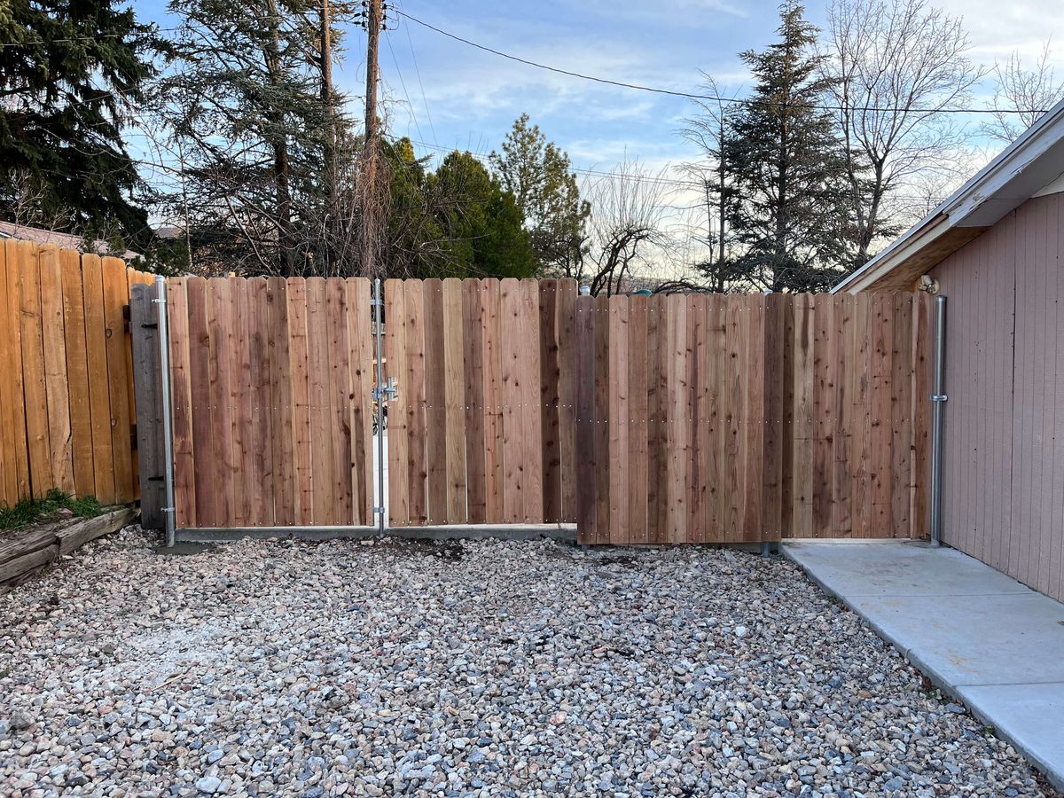 Wood privacy fence with a double drive gate across a gravel driveway in Bluffdale, UT
