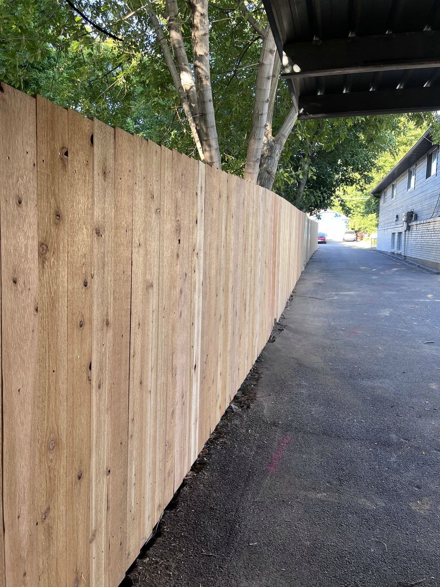 Tall wood privacy fence running along a paved drive beside a house in West Jordan, UT